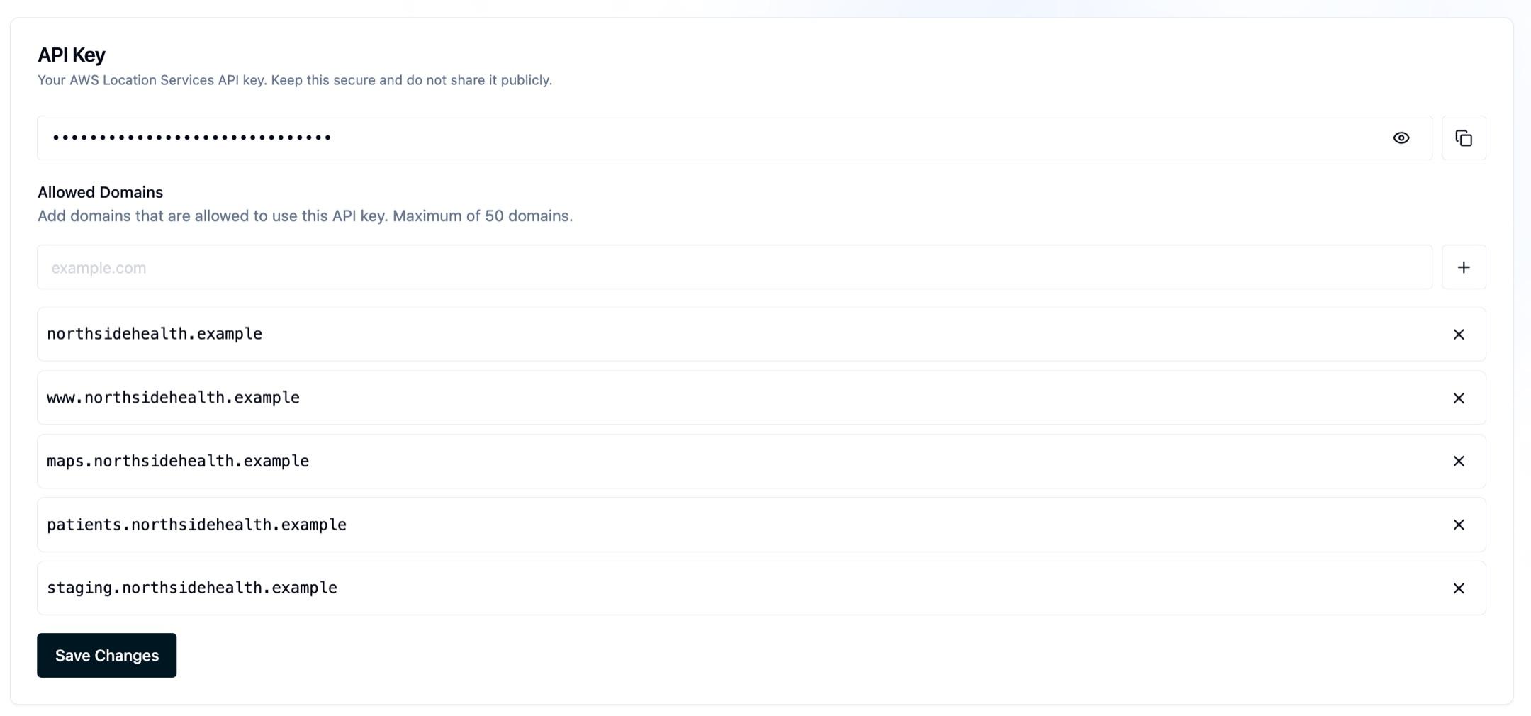 The Advanced Location API Key panel with the AWS Location Services key masked behind a reveal toggle and a copy button, above an Allowed Domains list containing five clinic subdomains and a Save Changes button